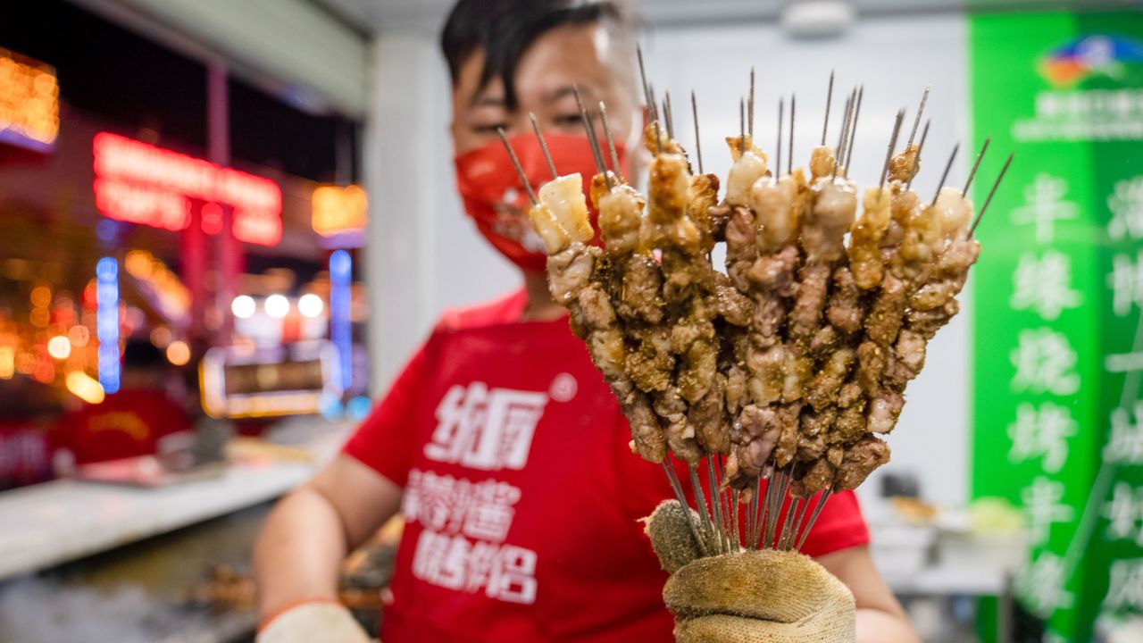 A shop owner shows off grilled meat during a barbecue festival on April 29, 2023 in Zibo, eastern  China. The city Zibo became a tourism hot spot after videos of its barbecue went viral online. 